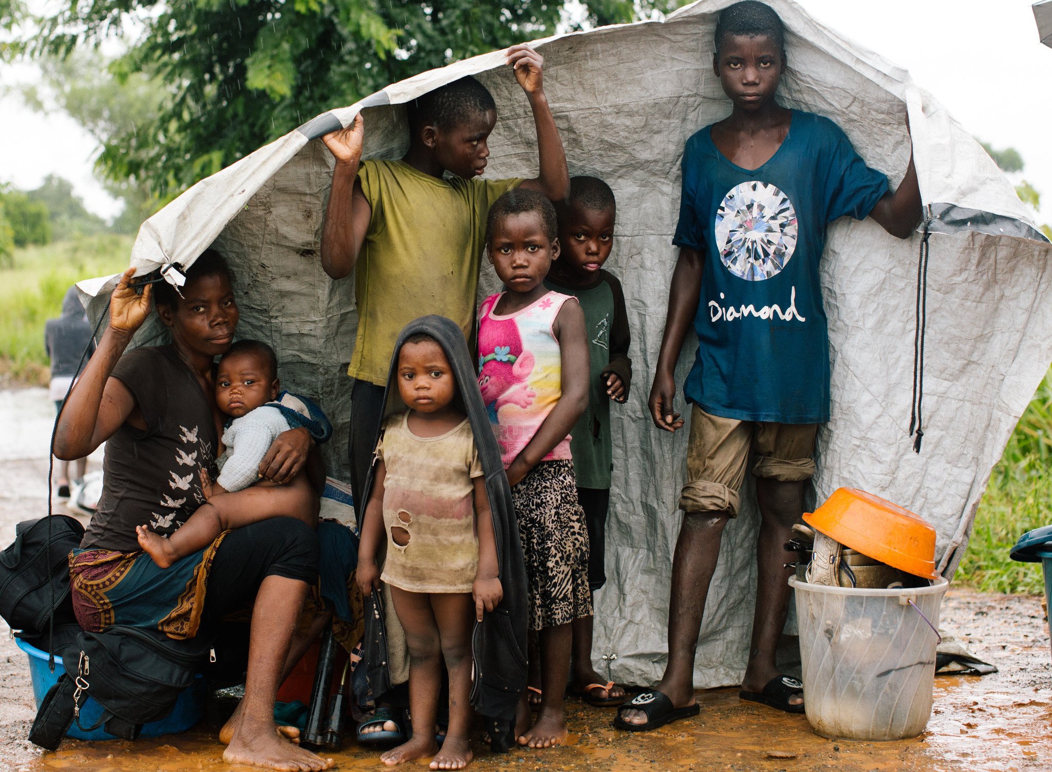 Every family at the evacuation centre has their own story of escape. Here, Maria, 31, and her six children with their only belongings are sheltering from the rain by the side of the road. Just 24 hours before this photo was taken, the rain came and the river banks burst causing their home to flood. Fearing another cyclone was coming, they gathered all their life belongings and left for higher ground. (Photo: Elena Heatherwick / Oxfam)